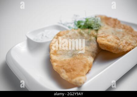 Cheburek oder gebratener Teigkuchen mit Fleischgefühl und Sauce auf weißem Hintergrund Stockfoto