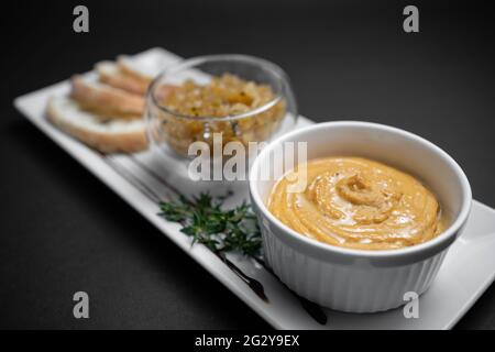 Nahaufnahme von Gänseleber-Pastete mit Apfelchutneys und Brot auf schwarzem Hintergrund Stockfoto