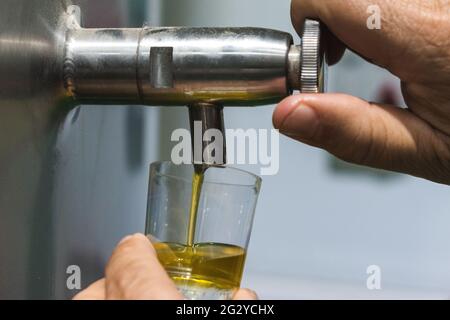 Nahaufnahme der Hand eines Mannes, der einen Hahn mit extra nativem Olivenöl öffnet Stockfoto