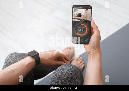 Frau mit Smart Watch und Telefon in der Hand Training Stockfoto