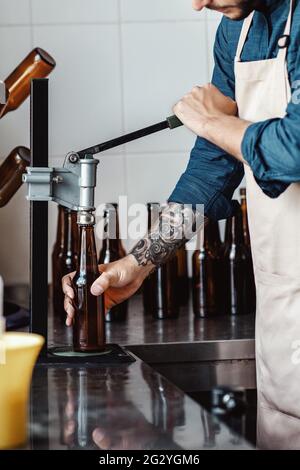 Junger Mann arbeitet in der Bierfabrik. Brauer mit Industrieanlagen in der Brauerei Stockfoto