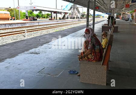 Beawar, Rajasthan, Indien, 13. Juni 2021: Rajasthani-Frau sitzt mit ihrem Kind und wartet auf den Zug am Bahnhof während der Wochenendsperrung aufgrund der COVID-19-Pandemie in Beawar. Kredit: Sumit-Samarwat/Alamy Live Nachrichten Stockfoto