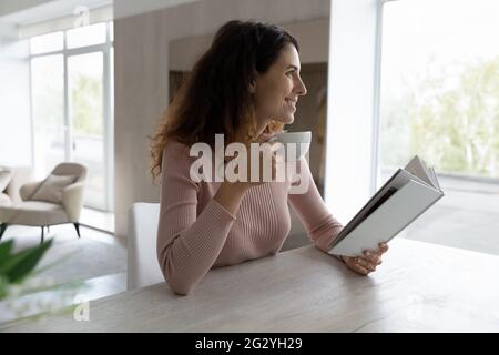 Lächelnde Latino Frau trinken Kaffee Buch zu Hause lesen Stockfoto