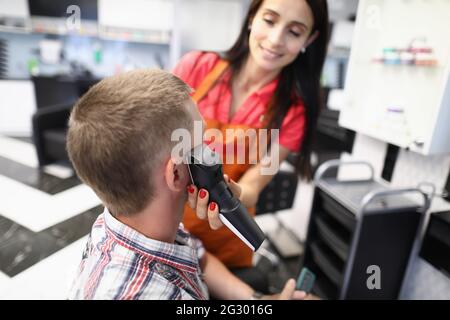 Master Friseur schneidet jungen Mann mit Haarschneider im Schönheitssalon Stockfoto