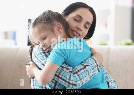 Das kleine Mädchen umarmt sich mit ihrer Mutter in sanfter Umarmung Stockfoto