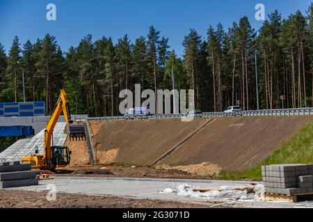 Der Bagger bereitet die Baustelle für den Bau der Straße vor. Orange Baumaschinen. Erdbewegungsmaschinen auf Straßenarbeiten Stockfoto