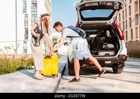 Paar sammeln für Road Trip. Putting Taschen auf Auto-Kofferraum. Sommerferien Stockfoto