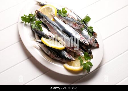 Rohe Sardinen mit Zitrone und Petersilie isoliert auf weißem Hintergrund. Direkt darüber. Stockfoto