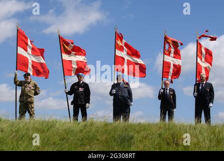 13. Juni 2021, Dänemark, Sønderborg: Dänische Veteranen halten dänische Nationalflaggen, während sie an einer Zeremonie in der Düppeler Schanze (Kongeskansen Dybbøl Bank) bei Sønderborg (Sonderburg) teilnehmen. Bundespräsident Steinmeier und seine Frau sind anlässlich des 100. Jahrestages der Grenzziehung zwischen Deutschland und Dänemark im Jahr 1920 zu einem zweitägigen Besuch in Dänemark. Die Feierlichkeiten mussten 2020 aus Corona-Gründen verschoben werden und werden nun wieder gutgemacht. Foto: Bernd von Jutrczenka/dpa Stockfoto