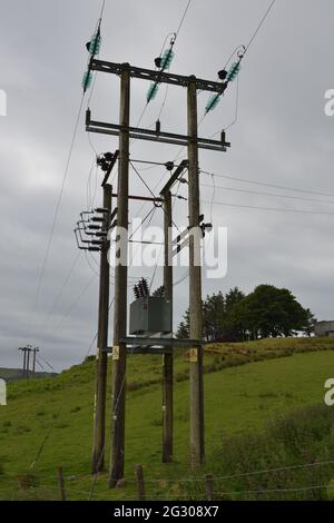Hölzerner Strommast mit einem Masttransformator (PMT) und einer Anschlussstelle auf der Isle of Kerrera, Großbritannien. Stockfoto