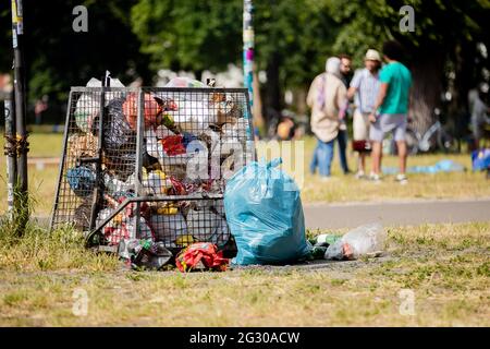 Berlin, Deutschland. Juni 2021. Ein voller Mülleimer im Volkspark Friedrichshain. In mehreren Berliner Parks haben große Partys in der Nacht bis zum Samstag die Polizei auf den Plan gerufen. Auch wegen Verletzungen der Hygieneanforderungen bei der Pandemie hat die Polizei einige Grünflächen geräumt, teilte die Behörde am Samstag mit. Quelle: Christoph Soeder/dpa/Alamy Live News Stockfoto