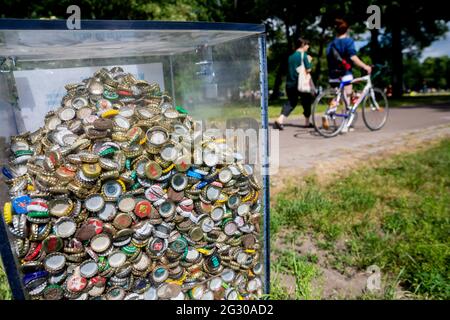 Berlin, Deutschland. Juni 2021. Ein transparenter Behälter mit Kronkorken im Volkspark Friedrichshain. In mehreren Berliner Parks haben große Partys in der Nacht bis zum Samstag die Polizei auf den Plan gerufen. Auch wegen Verletzungen der Hygieneanforderungen bei der Pandemie hat die Polizei einige Grünflächen geräumt, teilte die Behörde am Samstag mit. Quelle: Christoph Soeder/dpa/Alamy Live News Stockfoto