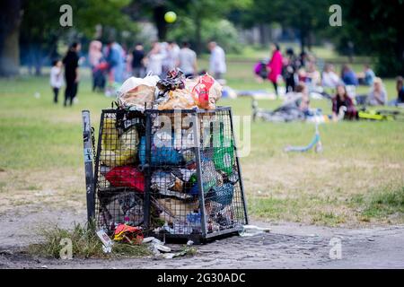 Berlin, Deutschland. Juni 2021. Ein voller Mülleimer im Volkspark Friedrichshain. In mehreren Berliner Parks haben große Partys in der Nacht bis zum Samstag die Polizei auf den Plan gerufen. Auch wegen Verletzungen der Hygieneanforderungen bei der Pandemie hat die Polizei einige Grünflächen geräumt, teilte die Behörde am Samstag mit. Quelle: Christoph Soeder/dpa/Alamy Live News Stockfoto