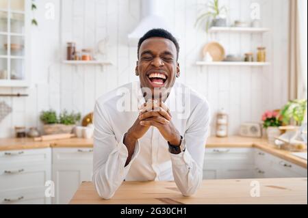 Lachender Mann, der an der Theke in der Küche sitzt Stockfoto