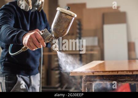 Prozess der Lackierung oder Sprühen von Holz durch automatische Spray in der professionellen Tischlerei, industrielles Konzept Stockfoto