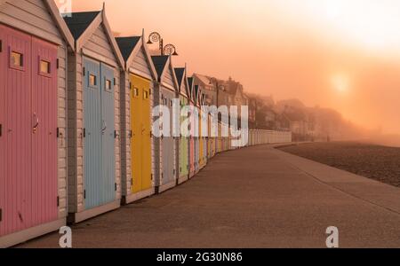 Bunte Strandhütten in einer Reihe, bei Sonnenaufgang auf der Promenade bei Lyme Regis, Jurassic Coast, Dorset mit Kopierraum Stockfoto