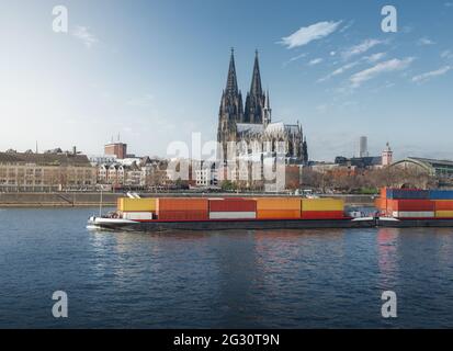 Frachtschiff, das Container auf dem Rhein transportiert, mit dem Kölner Dom im Hintergrund - Köln, Deutschland Stockfoto