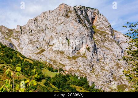 Bulnes de Arriba, El Castillo, unter einem großen Berg aus Kalkstein, im Nationalpark Picos de Europa. Bulnes, Cabrales, Asturien, Spanien, Euro Stockfoto