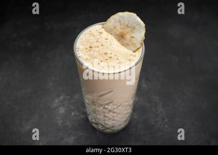 Smoothies aus Mango und Banane im Glas auf einem dunklen rustikalen Hintergrund. Gesunde Ernährung, Detox-Diät. Kopiespeicherplatz in der Draufsicht. Stockfoto