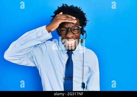 Der junge afroamerikanische Mann, der das Headset eines Callcenters trug, war gestresst und frustriert, mit der Hand auf dem Kopf, überrascht und wütend Stockfoto