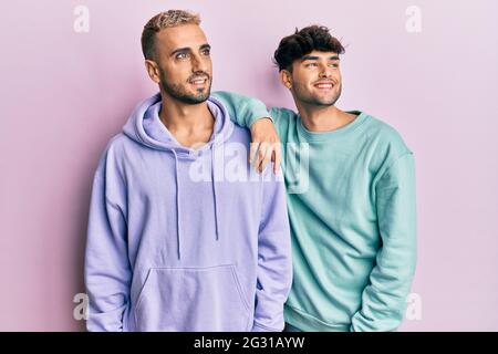 Homosexuell schwule Paar zusammen stehend in lässigen Kleidern Blick weg zur Seite mit Lächeln auf dem Gesicht, natürlichen Ausdruck. Lachen zuversichtlich. Stockfoto
