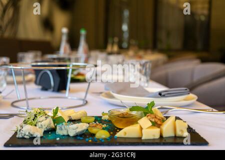 Verschiedene Snacks auf einem schwarzen Steinteller auf einem Restauranttisch auf einem Fensterhintergrund Stockfoto