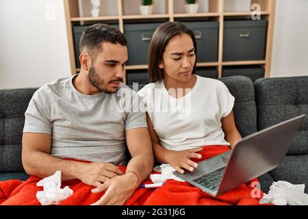 Junge lateinamerikanische kranke Paare, die zu Hause eine medizinische Fernsulation mit einem Laptop haben. Stockfoto