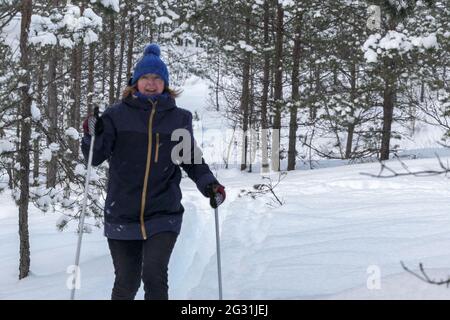 Happy Senior Skifahren in verschneiten Waldhügel. Ältere aktive Lebensweise im Winter. Senior Frau Langlauf Telemark Skifahren in verschneiten Wald. Aktive Leben Stockfoto