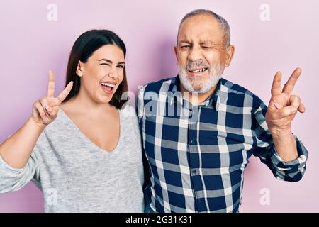 Hispanischer Vater und Tochter in legerer Kleidung lächeln mit glücklichen Gesicht winken auf die Kamera tun Siegeszeichen mit den Fingern. Nummer zwei. Stockfoto