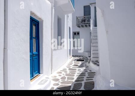 Mykonos, Griechenland. Weiß getünchte Gebäude, enge gepflasterte Straße. Chora Dorf traditionelle Architektur in weißen und blauen Farben. Sommerurlaub Stockfoto