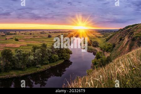 Wunderschöne Sommerlandschaft Sonnenaufgang über dem Fluss mit grüner Wiese Stockfoto