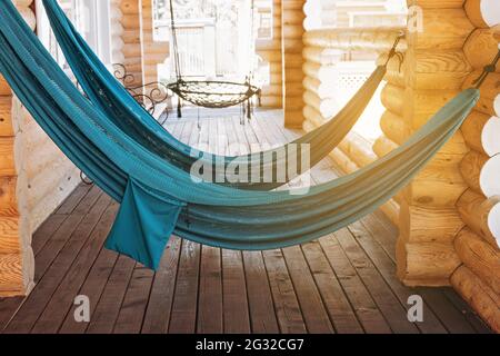 Hängende Hängematten zum Entspannen auf der offenen Terrasse eines Holzhauses. Erholung auf dem Land und Entspannung in der Natur im Sommer. Speicherplatz kopieren. Stockfoto