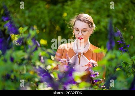 Junge intellektuelle Frau in Kleidung der 1940er Jahre in einem Garten Stockfoto