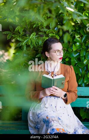 Junge intellektuelle Frau in Kleidung der 1940er Jahre in einem Garten Stockfoto