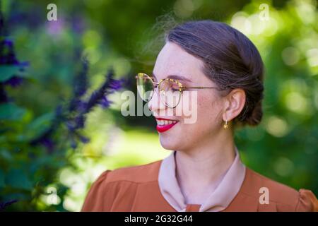 Junge intellektuelle Frau in Kleidung der 1940er Jahre in einem Garten Stockfoto