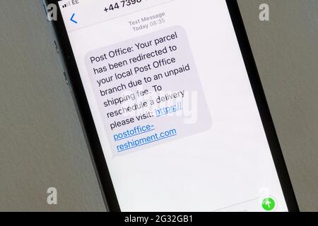 Eine auf einem iphone angezeigte Betrugsmeldung, die vorgibt, von der Post zu kommen, um eine Paketzustellung zu verschieben. Stockfoto