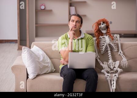 Mann, der auf dem Sofa mit weiblichem Skelett sitzt Stockfoto