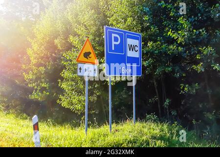 Straßenschilder auf der Autobahn. Parkplatz und Toilette nach 16 km. Achtung Ampphibische Kröten und Frösche überqueren die Straße. Stockfoto