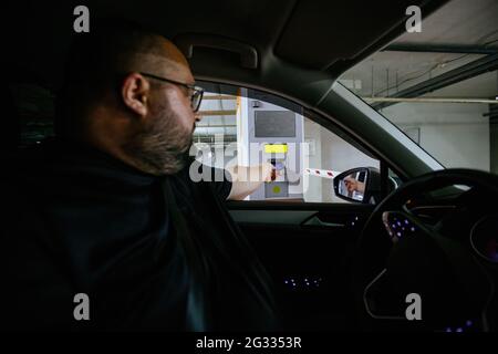 Der Mann im Auto zahlt für die Tiefgarage am Zahlungsterminal. Stockfoto