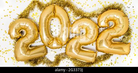 Goldene 2022 Luftballons. Gold metallic Folie Zahlen für Happy New Year Feier auf weißem Hintergrund mit Konfetti-Sternen und Girlande Stockfoto