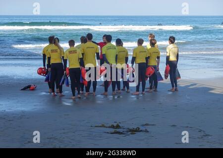 Eine Gruppe von Rettungsschwimmern am Huntington Beach mit Schwimmflossen und Rettungsausrüstung am Ufer. Kalifornien, USA Stockfoto