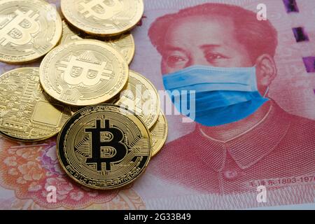Beschränkungen der Kryptowährung in China nach der COVID-19-Pandemie. Konzept. Bild von Bitcoin-Münzen auf 100 Yuan-Note mit angewendetem Anti-Virus-Gesicht m platziert Stockfoto