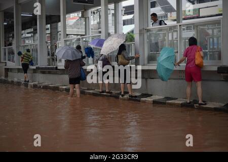 Jakarta, Indonesien. Februar 2015. Fußgänger, die beim Gehen versuchen, dem Hochwasser zu entgehen, indem sie an der Seite einer Trans-Jakarta-Bushaltestelle in der Thamrin-Straße, einer der wichtigsten Straßen in Jakarta, hängen, nachdem ein kontinuierlicher Regen die indonesische Hauptstadt überflutet hatte. Stockfoto