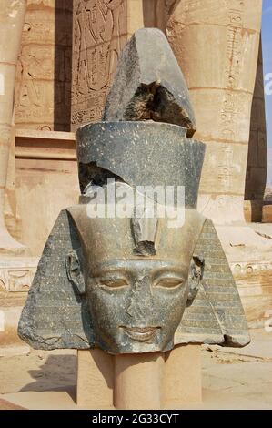 Beschädigte Skulptur des Kopfes des großen ägyptischen Pharao Ramses II. Am Wahrzeichen Ramasseum am Westufer des Nils in Luxor, Ägypten. Stockfoto