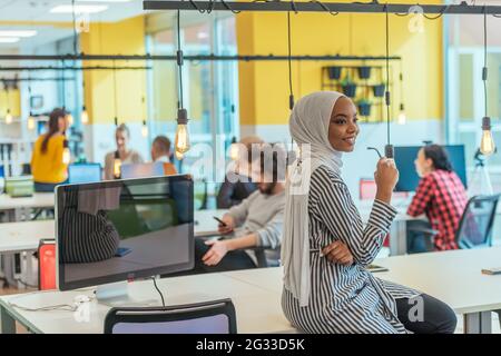 Trait einer schwarzen (afroamerikanischen) weiblichen muslimin, die in einem modernen Geschäftsbüro steht, während sie einen Hijab trägt. Stockfoto