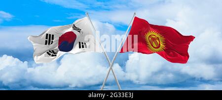 Flaggen von Südkorea und Kirgisistan winken im Wind auf Fahnenmasten gegen den Himmel mit Wolken am sonnigen Tag. Symbolisieren Beziehung, Dialog zwischen zwei Stockfoto