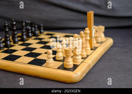 Holzschachbrett und Stücke mit einem hölzernen Kleiderpflock, die für einen fehlenden weißen König stehen. Stockfoto