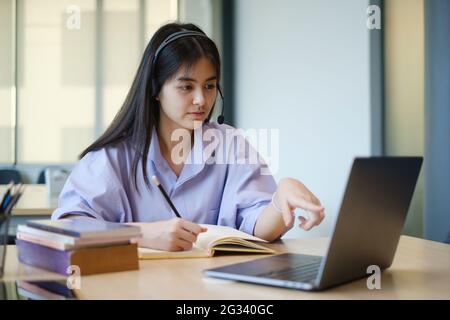 Ein Mädchen übt vor dem Online-Kurs per Video die Grundkursübungen auf dem Laptop. Soziale Distanzierung.Bleib zu Hause. Neuer Normalwert. Covid-19 Coronavirus-Konzept. Stockfoto