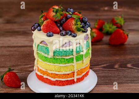 Regenbogen-Biskuitkuchen mit frischen Beeren verziert. Stockfoto