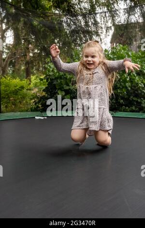 Lynwood, Washington, USA. 4-jähriges Mädchen, das auf ihrem Trampolin bis auf die Knie hüpft. (MR) Stockfoto